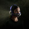 Une femme porte un casque d'écoute auquel est attaché un masque technologique qui purifie l'air.