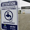 Une affiche devant une clôture indique une source d'eau potable.
