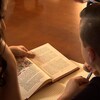 Une mère aide son fils dans ses lectures. Ils sont installés côte à côte à une table de cuisine.