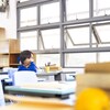Un écolier assis à sa table regarde une fenêtre de classe entrouverte.