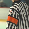 Un écusson de Hockey Canada figure sur l'épaule d'un arbitre en uniforme. 
