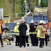 Des policiers, des ambulanciers et des membres d'une équipe de sauvetage technique sont massés derrière un cordon de sécurité sur un chantier.