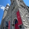 Des bannières rouges avec le logo de The United People of Canada accrochées à la façade de l'église Ste-Brigid.