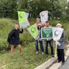 Cinq personnes tenant chacune une pancarte sur laquelle on lire : protéger le marais d'Eisner Cove.