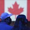 Des électeurs devant un drapeau du Canada.