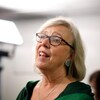 Habillée de vert, Elizabeth May pose devant une lampe.