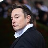 Vêtu d'un complet, Elon Musk se tourne vers le photographe.
