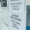 Des affiches « Nous embauchons » sur la porte d'un commerce.