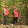 Émilie Cormier, dans les bois avec une autre femme, toutes deux vêtues d'habits de chasse. 