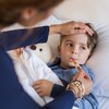 Une personne prend la température d'un enfant malade à l'aide d'un thermomètre buccal. 