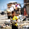 Un garçon palestinien tient un pot de nourriture dans une rue.