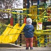 Un enfant se tient face à un module dans un parc dont l'accès est bloqué à l'aide de ruban.