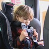 Un enfant attache lui-même le harnais de son siège d’auto.