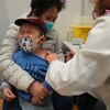 Un petit garçon pleure dans les bras de sa mère en recevant un vaccin.
