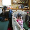 deux enfants autochtones dans une maison. L'un est assis sur un lit de camp, l'autre dans un lit pour bébé.