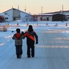 Deux enfants marchent sur une route enneigée.