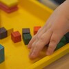La main d'un enfant attrape des jouets en bois colorés. 