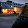 Une femme se tient debout devant un hôpital. 
