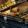 Des gens achètent des fruits et légumes dans une épicerie.