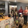 7 jeunes élèves de l'équipe Francobotqiue en photo à côté d'une table et étagère garnie de robots et trophées. 