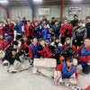 Un groupe de jeunes joueurs de hockey prend une pose d'équipe sur la glace en compagnie de quelques bénévoles.