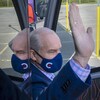 Erin O'Toole lève la main en sortant de son autobus de campagne.
