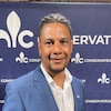 Ernesto Almeida devant un fond du Parti conservateur du Québec.