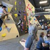 Des gens autour d'un mur d'escalade intérieur.