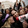 Deux femmes crient dans un mégaphone. Derrière elles, plusieurs autres femmes ont le poing levé. 