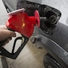 Une personne met de l'essence dans son véhicule, dans une station-service.