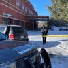 Des véhicules de polices devant un périmètre de sécurité autour d'un bâtiment.