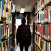 Un étudiant, de dos, dans une bibliothèque universitaire.
