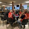 Quatre bénévoles de la Croix-Rouge discutent à une table au centre d'hébergement du Cégep de Chicoutimi.