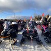 Des dizaines de motoneiges rassemblées sur un chemin enneigé.