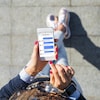 Vue en plongée sur l'écran d'un cellulaire utilisée par une femme qui montre une application de messagerie. 