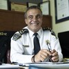 Portrait du policier, avec un grand sourire, dans son bureau.