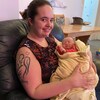 Une femme tient un bébé d'un mois dans un divan.
