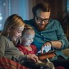 Une mère et un père regardent une tablette avec leur fille.