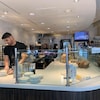 Un employé prépare des commandes derrière le comptoir d'une boulangerie.