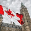 Drapeau du Canada qui flotte au rythme du vent en face du parlement canadien.