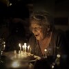 Une femme souffle les bougies de son gâteau de fête.