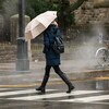 Une femme traverse une rue de Toronto sous la pluie.