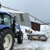 Un tracteur dans la neige avec une ferme.