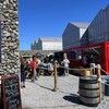 Une vingtaine de festivaliers discutent près des chapiteaux des distilleries sous un soleil radieux.