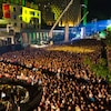 Une foule rassemblée sur la place des Festivals à Montréal la nuit. 