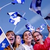 Une foule brandit des drapeaux québécois.