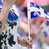 Une femme tient le drapeau québécois lors des célébrations de la fête nationale.