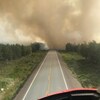 L'épaisse fumée d'un feu de forêt au bout d'une autoroute déserte.
