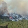 Photographie aérienne d'une forêt qui brûle en dégageant une épaisse fumée.