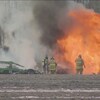 Des pompiers éteignent un tracteur en feu dans un champ.